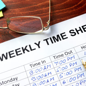 Paper with weekly time sheet on a table.