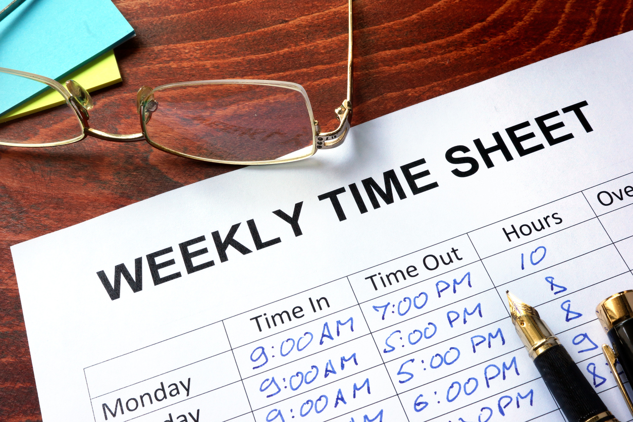 Paper with weekly time sheet on a table.